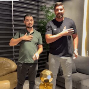 O North Esporte Clube iniciou uma nova era de acessibilidade e conexão com seu público. Em um encontro realizado na última quarta-feira (31/12), o presidente do clube, Victor Oliveira, e o vice-presidente da Associação dos Surdos de Montes Claros (ASMOC), Gabriel Couto, oficializaram o sinal em Libras que passa a identificar o time. A criação do sinal não foi aleatória; ela resultou de um estudo detalhado da identidade visual do clube, que possui a Fênix como símbolo. O gesto, feito com a mão sobre o peito próximo ao brasão, representa a asa da ave e o "brilho do ouro". VOZES DA LIDERANÇA Para o dono da SAF do North, Victor Oliveira, a iniciativa é um passo fundamental para aproximar o clube de todos os torcedores da região. "É uma honra estar recebendo aqui o nosso amigo Gabriel Couto. Quero convidar a todos da comunidade surda de Montes Claros e do Norte de Minas, para virem nos prestigiar nos jogos do North que serão bem acolhidos", afirmou o presidente. Gabriel destacou que a comunidade surda agora possui uma forma de expressar seu orgulho norte-mineiro de maneira autêntica e fundamentada na história do time. "Nós, nossa comunidade, estudamos toda a imagem visual do time até chegar no gesto certo para ser o sinal e identificar o brilho do ouro, o dourado", explicou Gabriel Couto. INCLUSÃO NA PRÁTICA Mais do que um gesto simbólico, a parceria estabelece protocolos reais de acesso. Ficou definido que os membros da comunidade surda poderão assistir aos jogos utilizando a carteirinha da ASMOC. Para garantir a organização, os interessados devem retirar os ingressos com 48 horas de antecedência. Essa ação reforça a importância da inclusão no esporte, transformando o estádio em um ambiente verdadeiramente democrático. Ao validar uma língua própria e garantir o acesso físico, o North Esporte Clube se posiciona como um exemplo de responsabilidade social, provando que a paixão pelo futebol não conhece barreiras de comunicação. O North Esporte Clube iniciou uma nova era de acessibilidade e conexão com seu público. Em um encontro realizado na última quarta-feira (31/12), o presidente do clube, Victor Oliveira, e o vice-presidente da Associação dos Surdos de Montes Claros (ASMOC), Gabriel Couto, oficializaram o sinal em Libras que passa a identificar o time. A criação do sinal não foi aleatória; ela resultou de um estudo detalhado da identidade visual do clube, que possui a Fênix como símbolo. O gesto, feito com a mão sobre o peito próximo ao brasão, representa a asa da ave e o "brilho do ouro". VOZES DA LIDERANÇA Para o dono da SAF do North, Victor Oliveira, a iniciativa é um passo fundamental para aproximar o clube de todos os torcedores da região. "É uma honra estar recebendo aqui o nosso amigo Gabriel Couto. Quero convidar a todos da comunidade surda de Montes Claros e do Norte de Minas, para virem nos prestigiar nos jogos do North que serão bem acolhidos", afirmou o presidente. Gabriel destacou que a comunidade surda agora possui uma forma de expressar seu orgulho norte-mineiro de maneira autêntica e fundamentada na história do time. "Nós, nossa comunidade, estudamos toda a imagem visual do time até chegar no gesto certo para ser o sinal e identificar o brilho do ouro, o dourado", explicou Gabriel Couto. INCLUSÃO NA PRÁTICA Mais do que um gesto simbólico, a parceria estabelece protocolos reais de acesso. Ficou definido que os membros da comunidade surda poderão assistir aos jogos utilizando a carteirinha da ASMOC. Para garantir a organização, os interessados devem retirar os ingressos com 48 horas de antecedência. Essa ação reforça a importância da inclusão no esporte, transformando o estádio em um ambiente verdadeiramente democrático. Ao validar uma língua própria e garantir o acesso físico, o North Esporte Clube se posiciona como um exemplo de responsabilidade social, provando que a paixão pelo futebol não conhece barreiras de comunicação. North lança sinal em libras e celebra inclusão